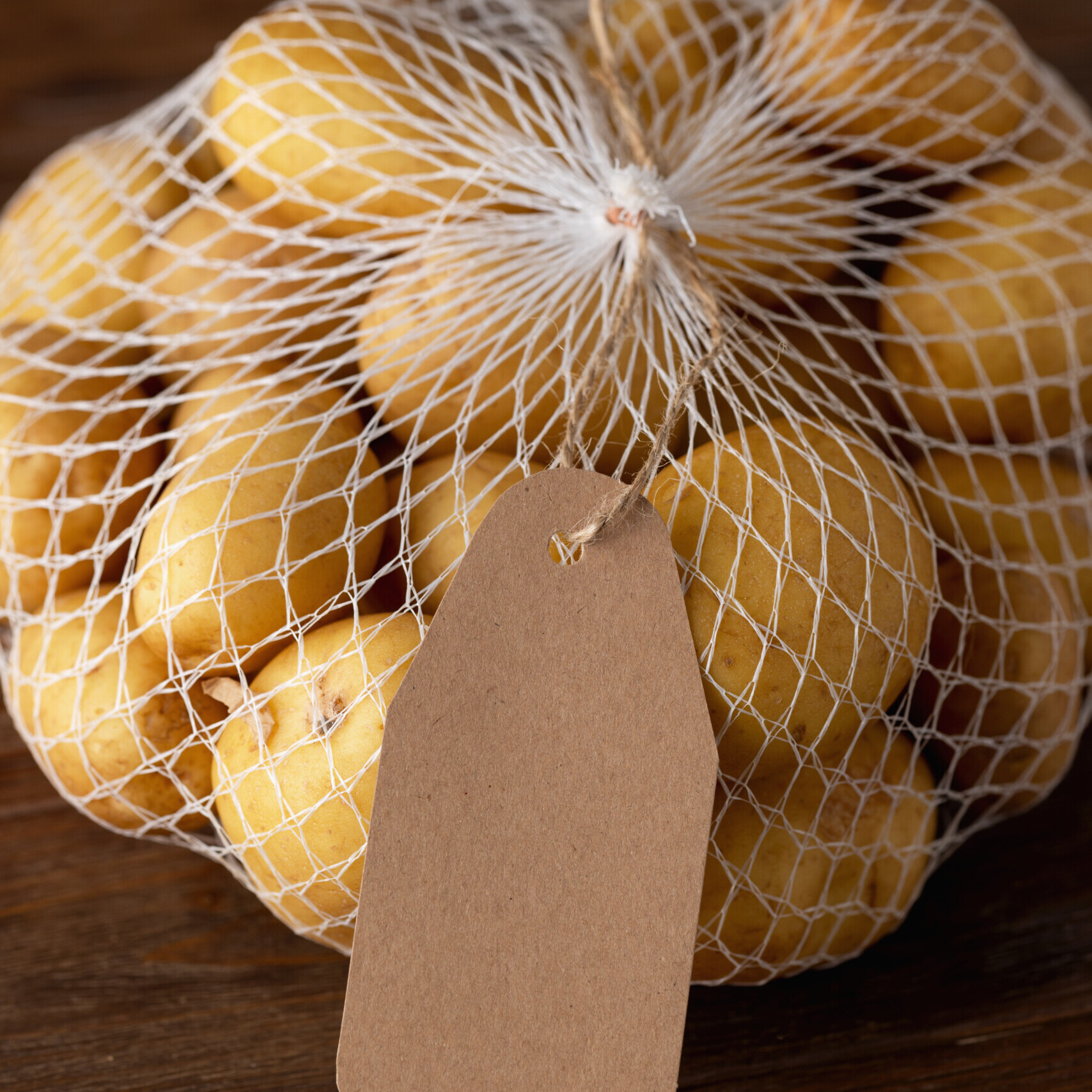 Grid with potatoes on a brown wooden background with an inscription label with empty space Grid with potatoes on a brown wooden background with an inscription label with empty space